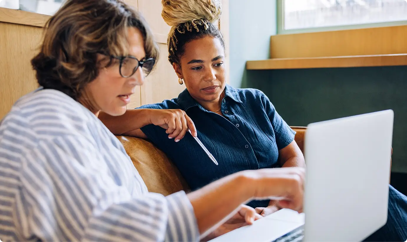 2 women in an office looking over a laptop