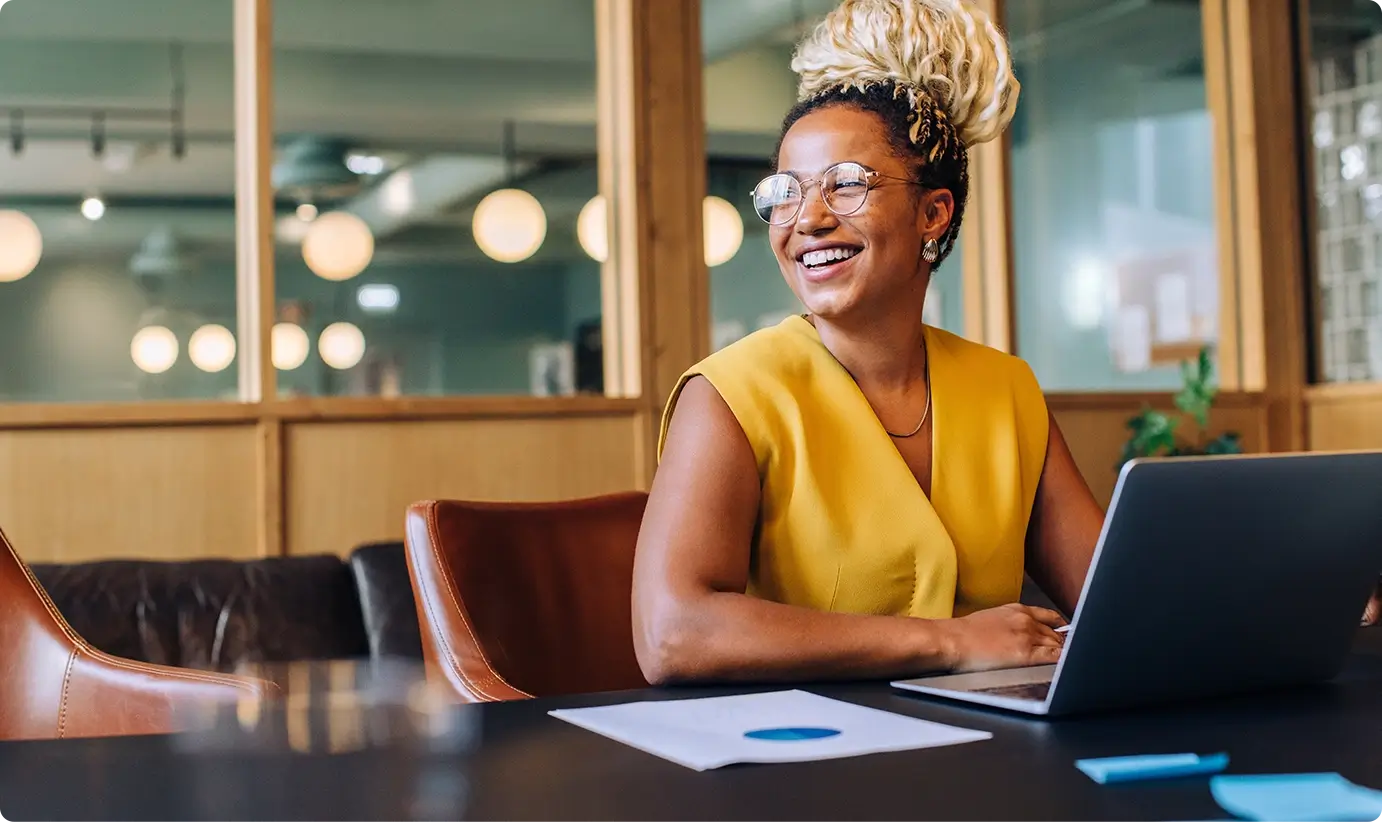 Woman in an office smiling next to laptop