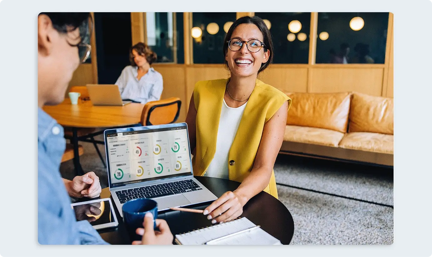 Woman in an office smiling next to Teamgage results on her laptop
