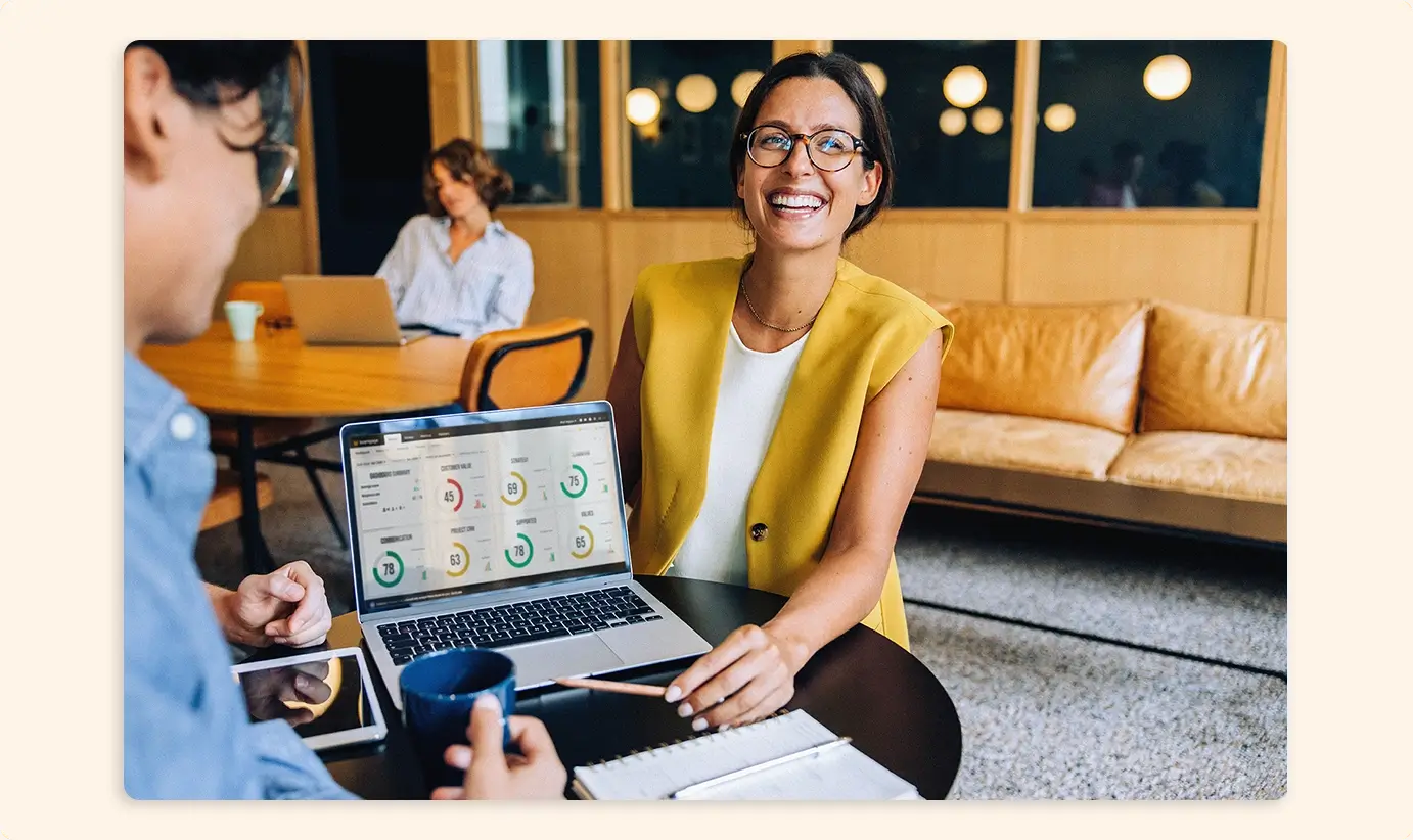 Woman smiling in an office next to a laptop with Teamgage results