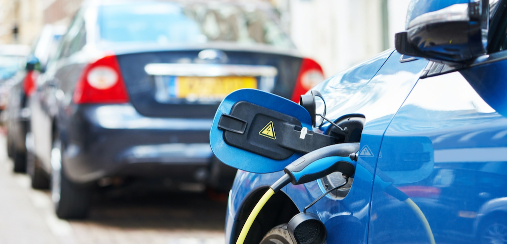 An EV charger plugged into a blue electric car, charging the vehicle's battery.