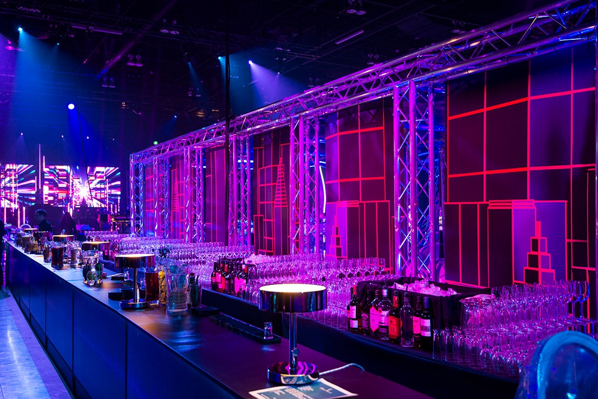 Pink neon-style cityscape graphics on truss structures behind the Celebrate City bar.
