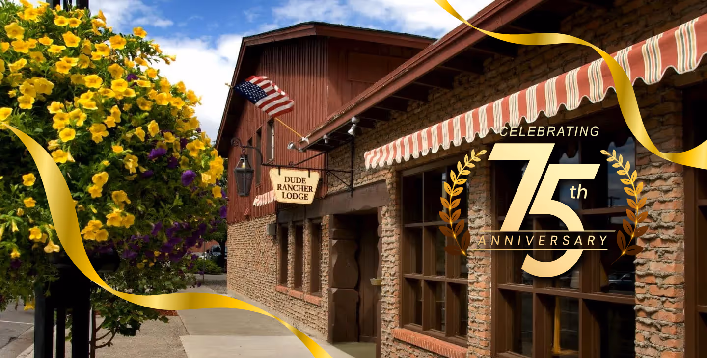 Brick and wood building of Dude Rancher Lodge with striped awning and an American flag, decorated for 75th anniversary celebration.