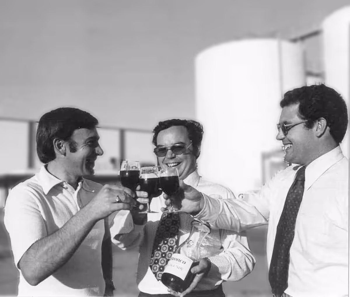 Black and white image of the three bronco founders, John, Fred, and Joseph toasting at the Ceres winery