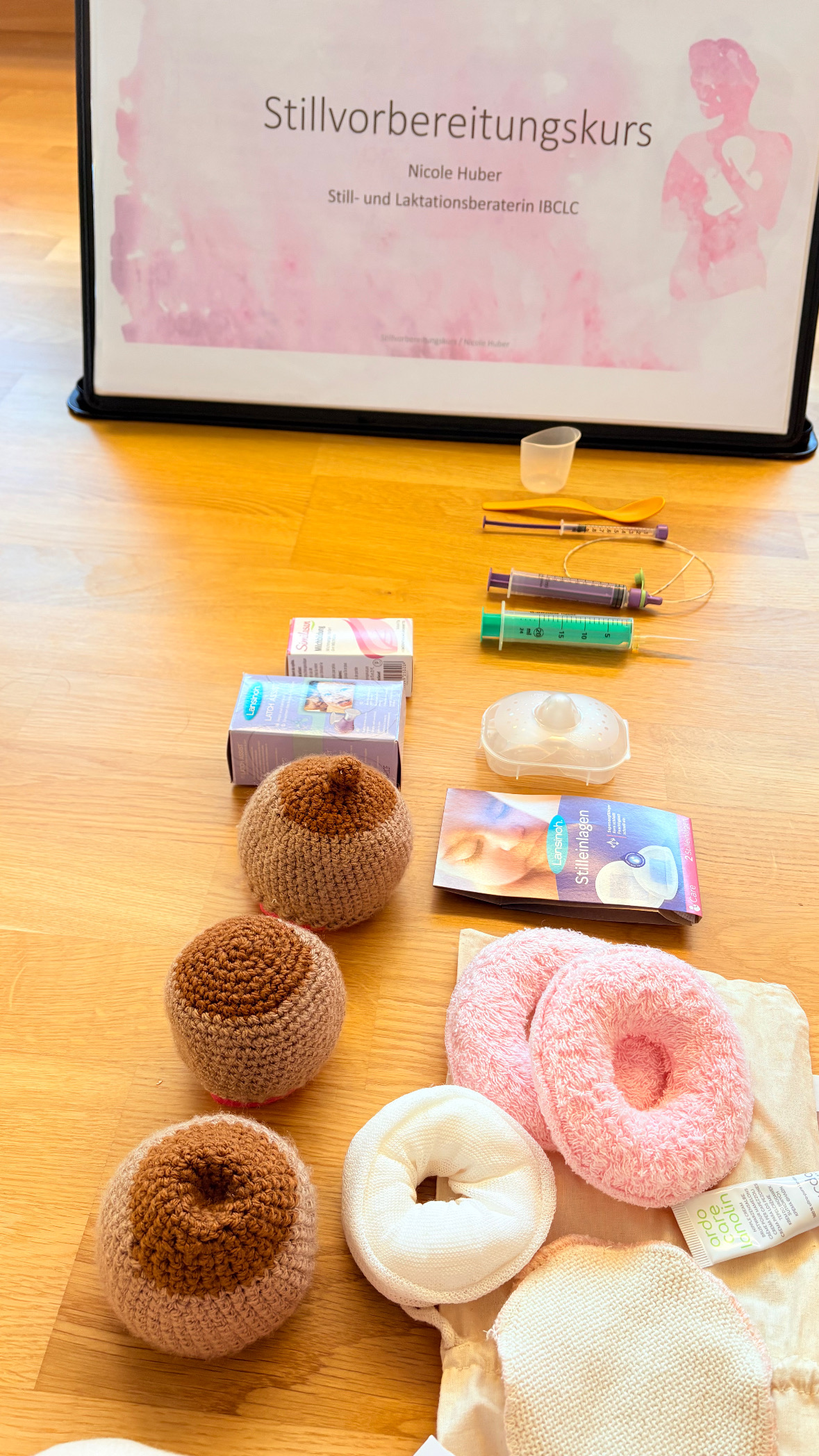 Tisch mit vielen Unterlagen rund ums Stillen: Bücher, Brustpumpe, Salbe und mehr.