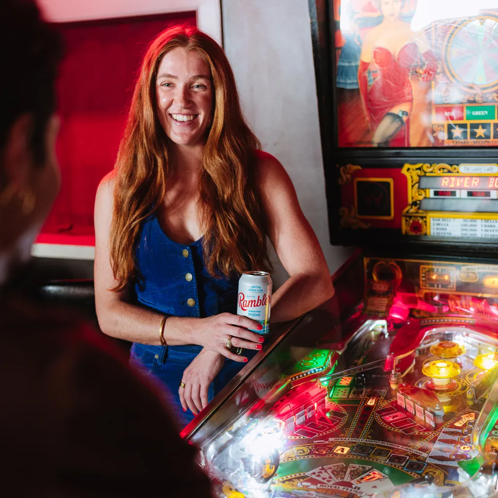 Rambler Sparkling Water Original flavor being enjoyed near a pinball machine