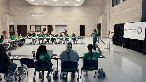 A presenter presenting and discussing topics in an open room with students