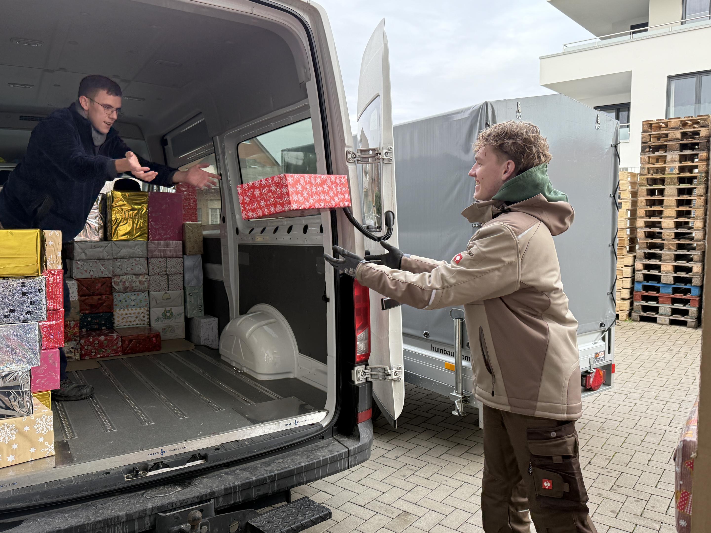 Helfer der Bibel-Mission verladen Weihnachtspäckchen in einen Transporter