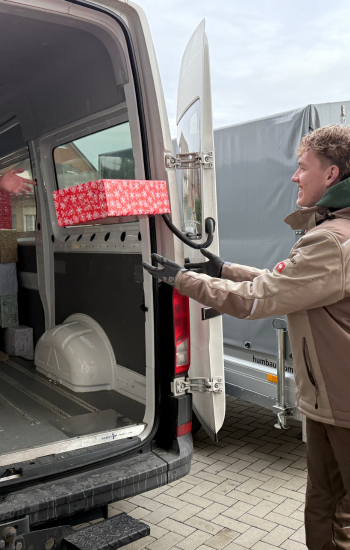 Helfer der Bibel-Mission verladen Weihnachtspäckchen in einen Transporter