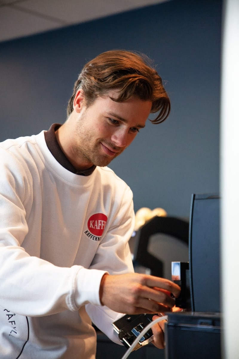 Servicetekniker fra Kaffeknappen justerer en kaffemaskin hos en bedriftskunde