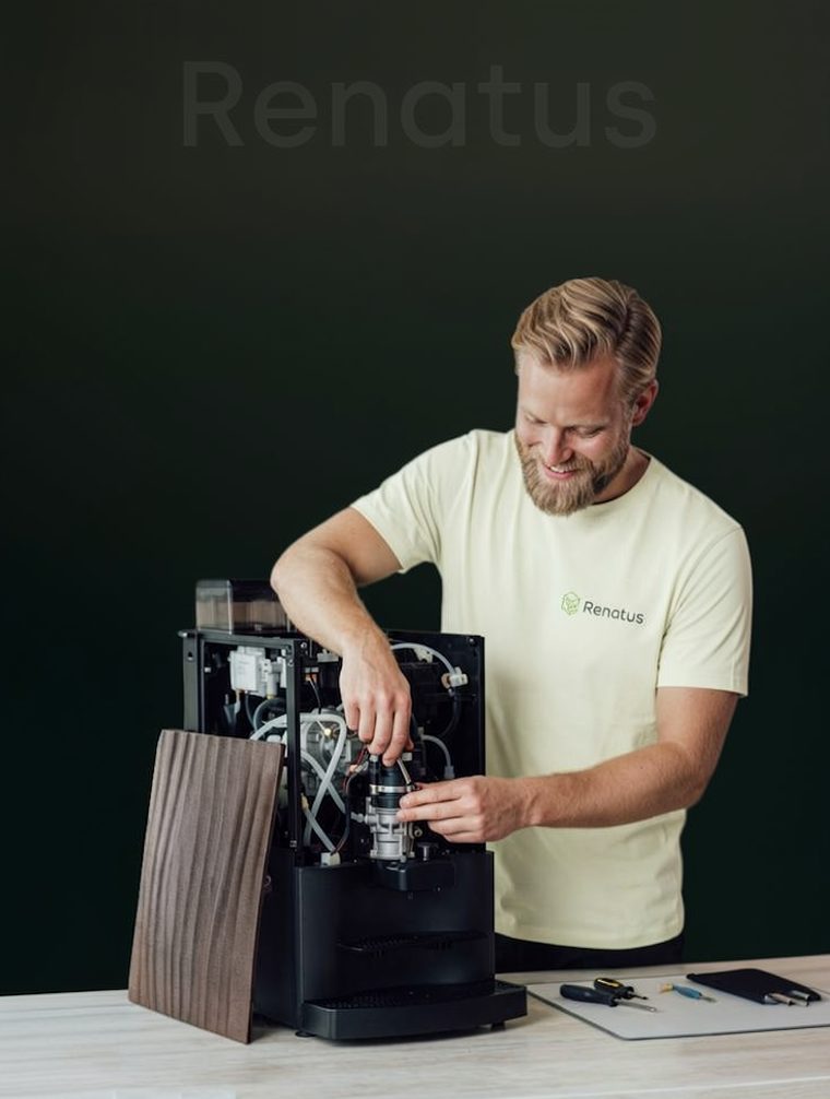 Tekniker som arbeider inne i en åpen kaffemaskin