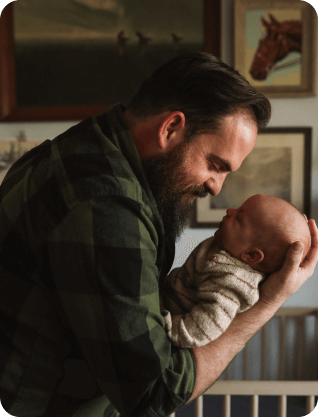 A man on a green and black fleece holding a baby.