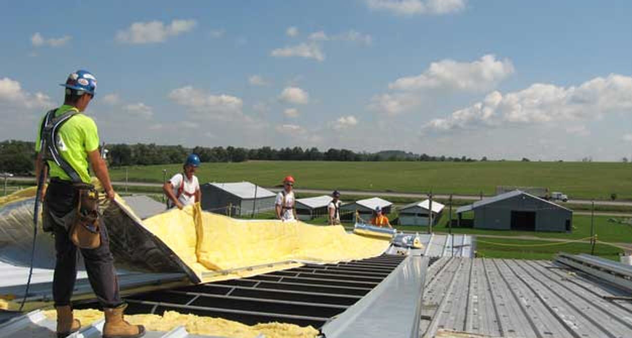 workers on a roof installing sheets of insulating material