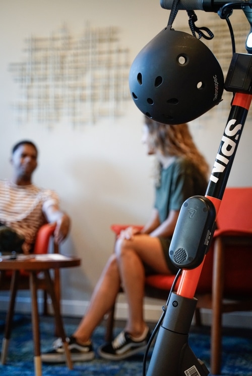 A Spin scooter next to two people having a meeting.