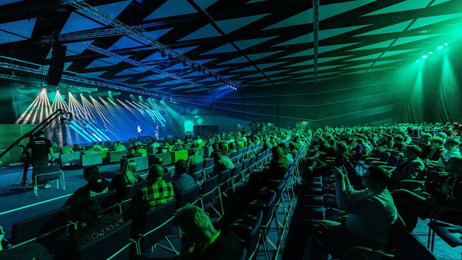 A busy conference hall with people sat watching a talk