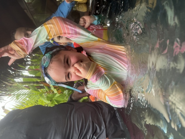 Laughing in the pool with goggles pushed up on her head