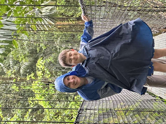 Mom and son smiling on the canopy bridge in rain ponchos