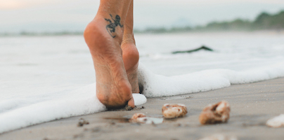 feet walking on beach at the edge of water