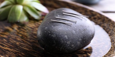 acupuncture needles lying on a stone
