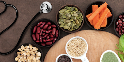 nutritious foods and herbs displayed in shape of heart with stethoscope on table