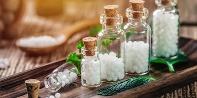 Clear glass bottles with cork tops holding homeopathic pellets with herbs