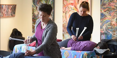 biofield tuning practitioners using tuning forks on patients lying on massage tables