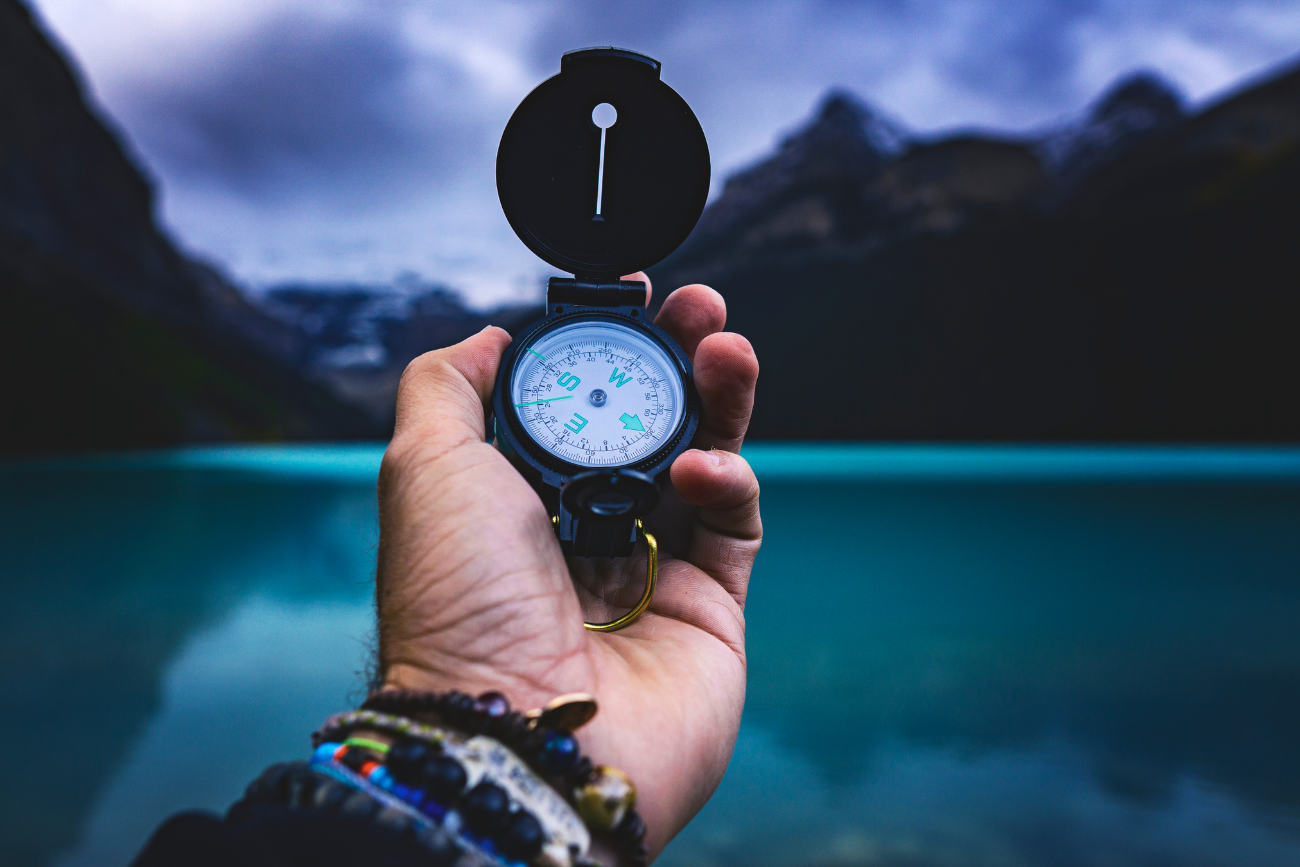 hand holding compass out with view of lake and mountains