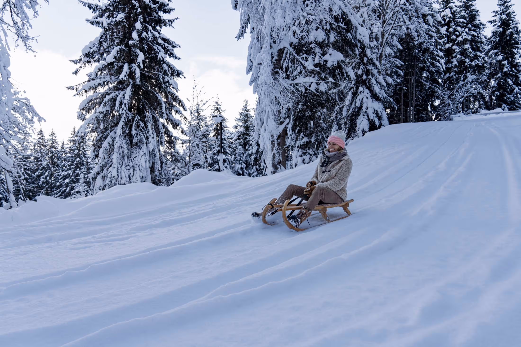 Eine Frau fährt mit dem Schlitten die Rodelbahn entlang.