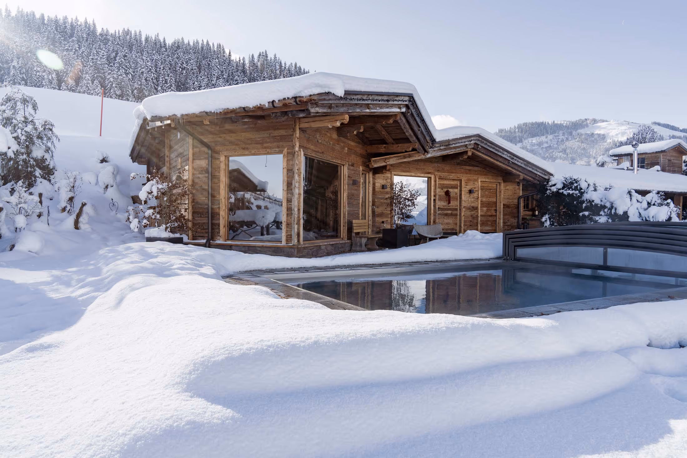 Tiefverschneites Saunahäuschen mit Outdoor-Swimmingpool.