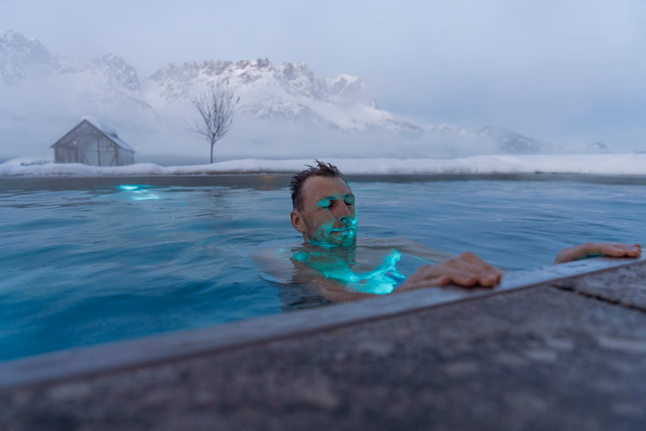 Ein Mann genießt das warme Wasser des Outdoor-Pools am Naschberghof.