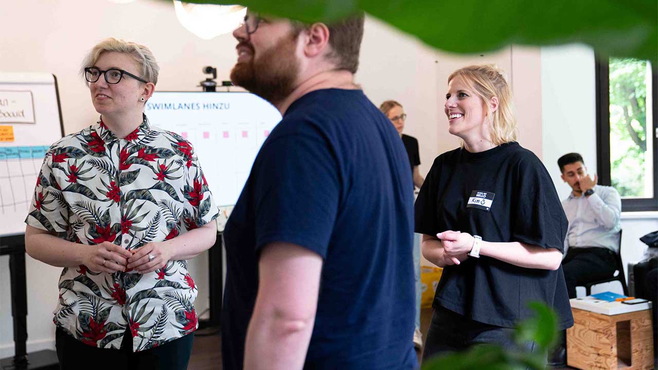 Eine Gruppe junger Erwachsener nimmt aktiv und gut gelaunt an einem Workshop in einem modernen Büro teil.