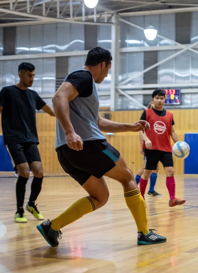 A male Futsal player kicks the ball upcourt