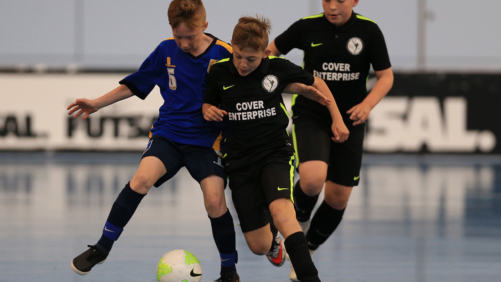 Two junior Futsal players jostle for the ball
