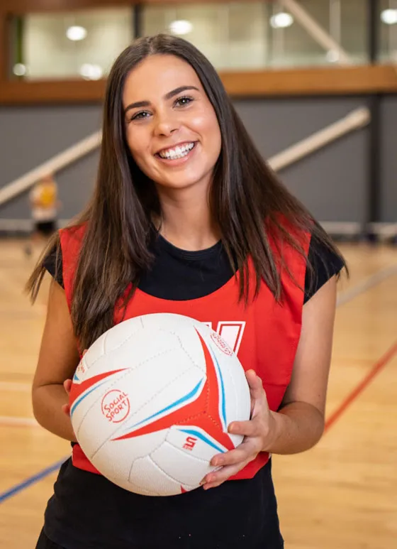 A girl smiles as she holds a netball