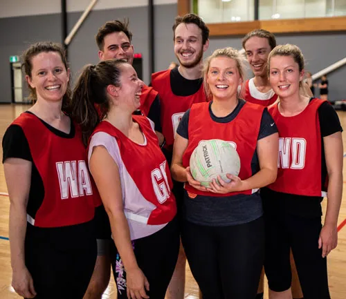 A social Netball team laugh as they stand for a team photo