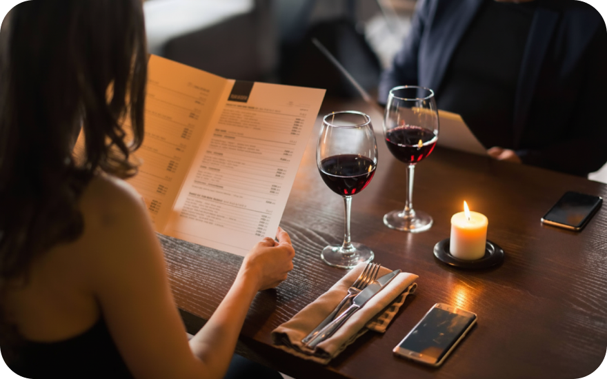 A couple is dining out at a restaurant and enjoying a glass of red wine each.