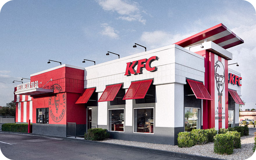 KFC restaurant exterior with Colonel Sanders logo, drive-thru lanes, and red signage in the United States.
