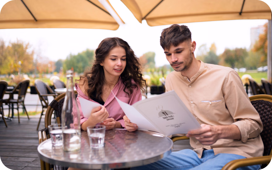 Couple on a restaurant date examining a menu, emphasizing clear menu transparency and informed choices.