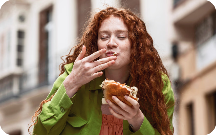 Person enjoying a burger at a table, showing approachable global flavors in everyday dining.