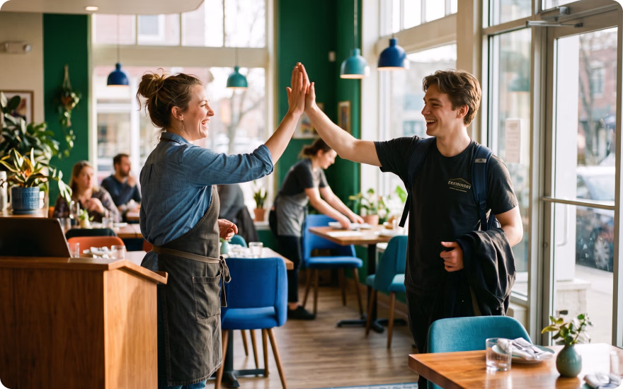 A restaurant manager gives a team member a high five as he ends his shift.