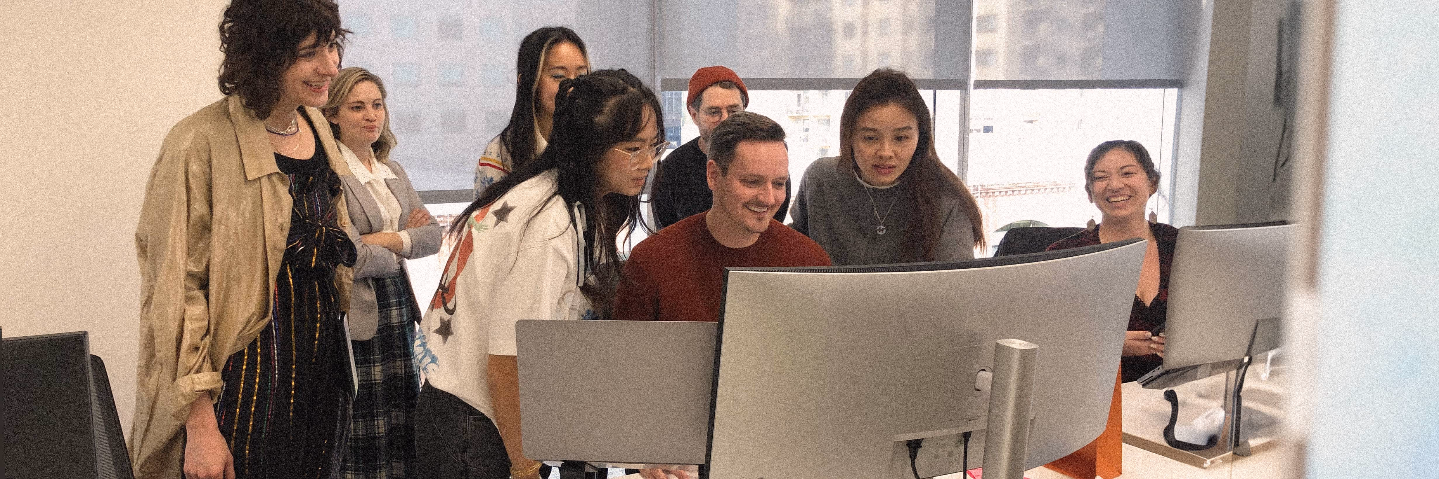 Photo of Nick surrounded by his team at a computer