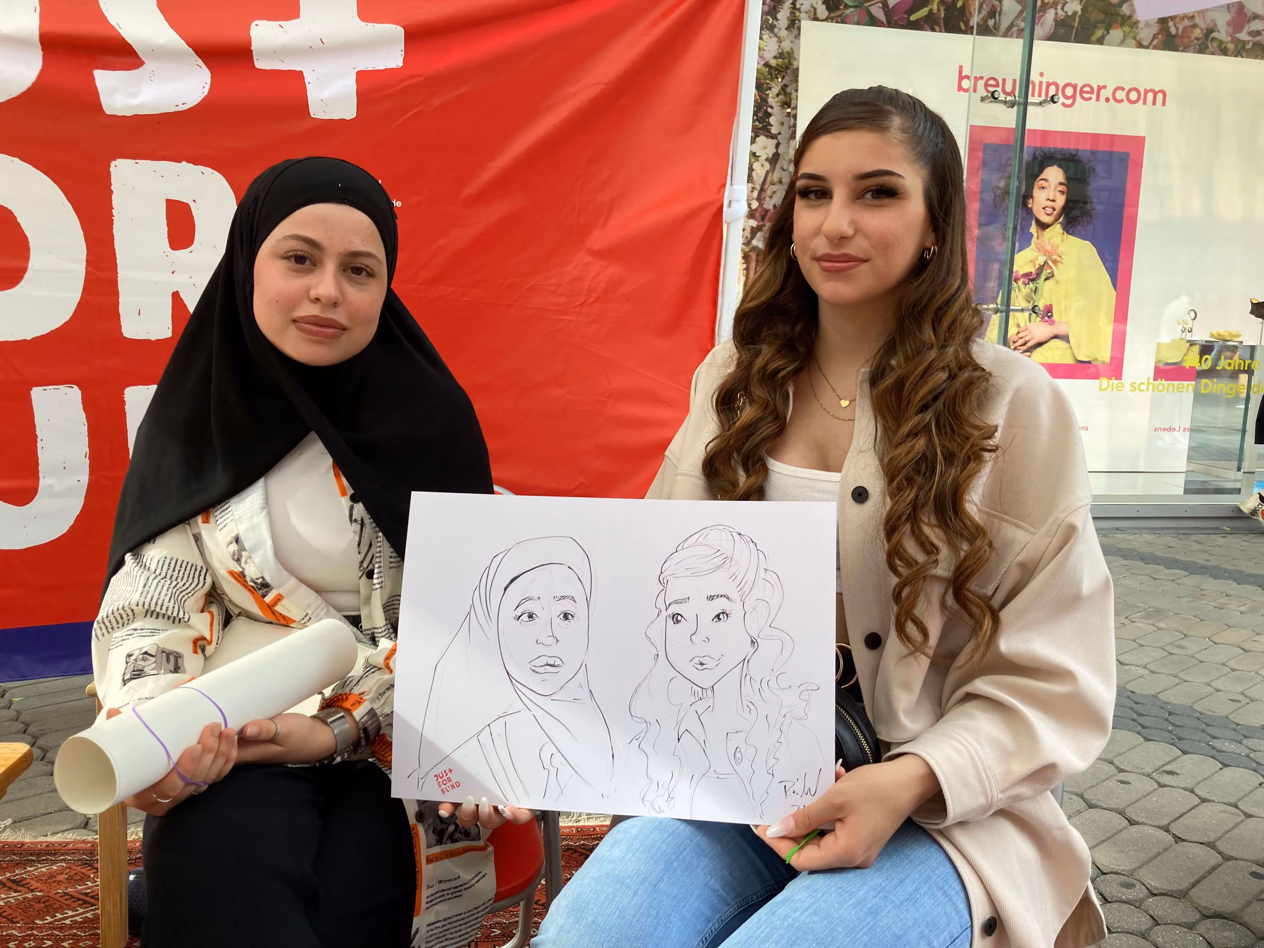 Two Women holding a handdrawn Portrait