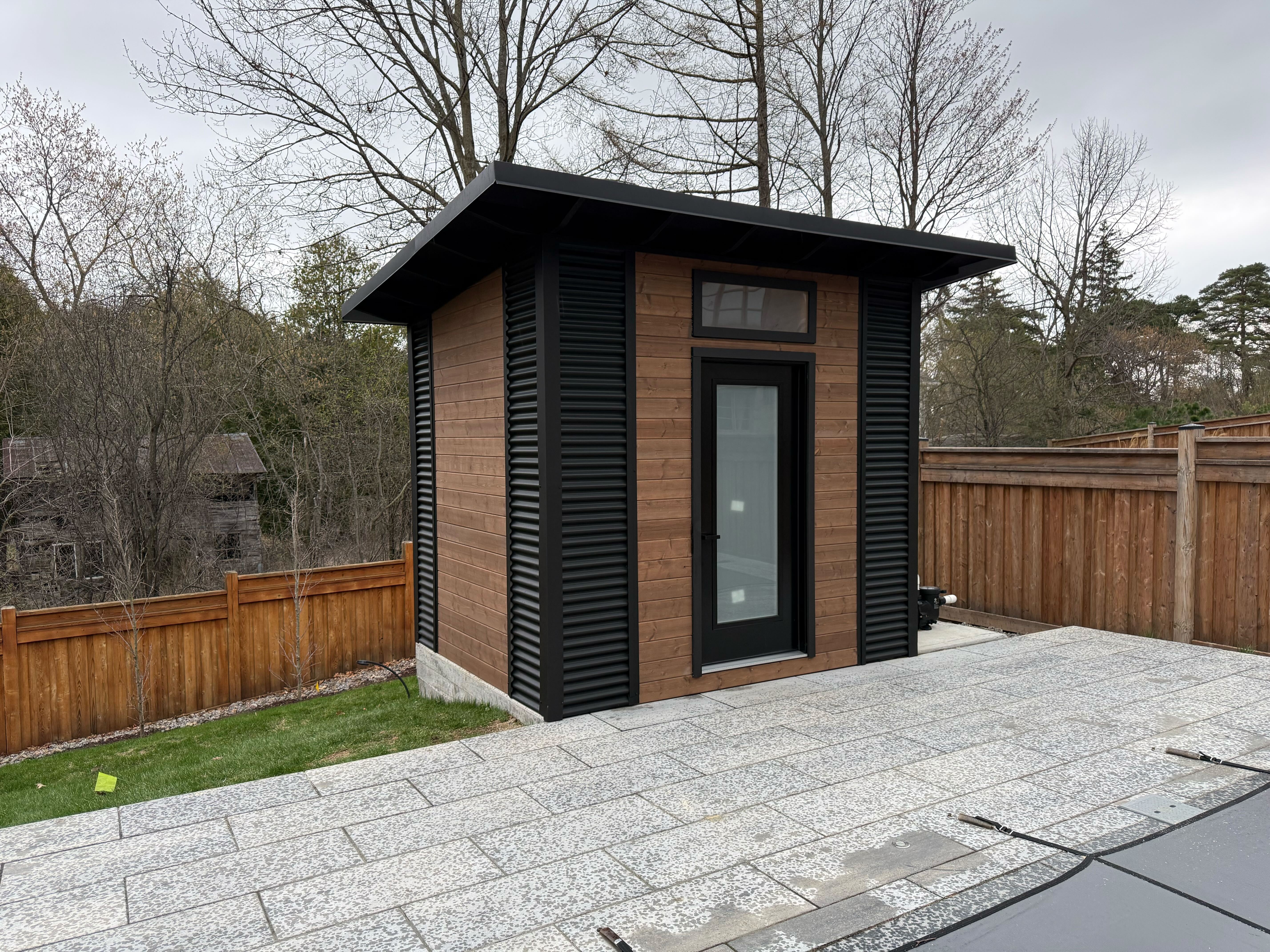 10x8 Advanced Shed with black corrugated steel siding and cedar-stained pine front wall installed in Aurora Ontario by Backyard Escape Studios.