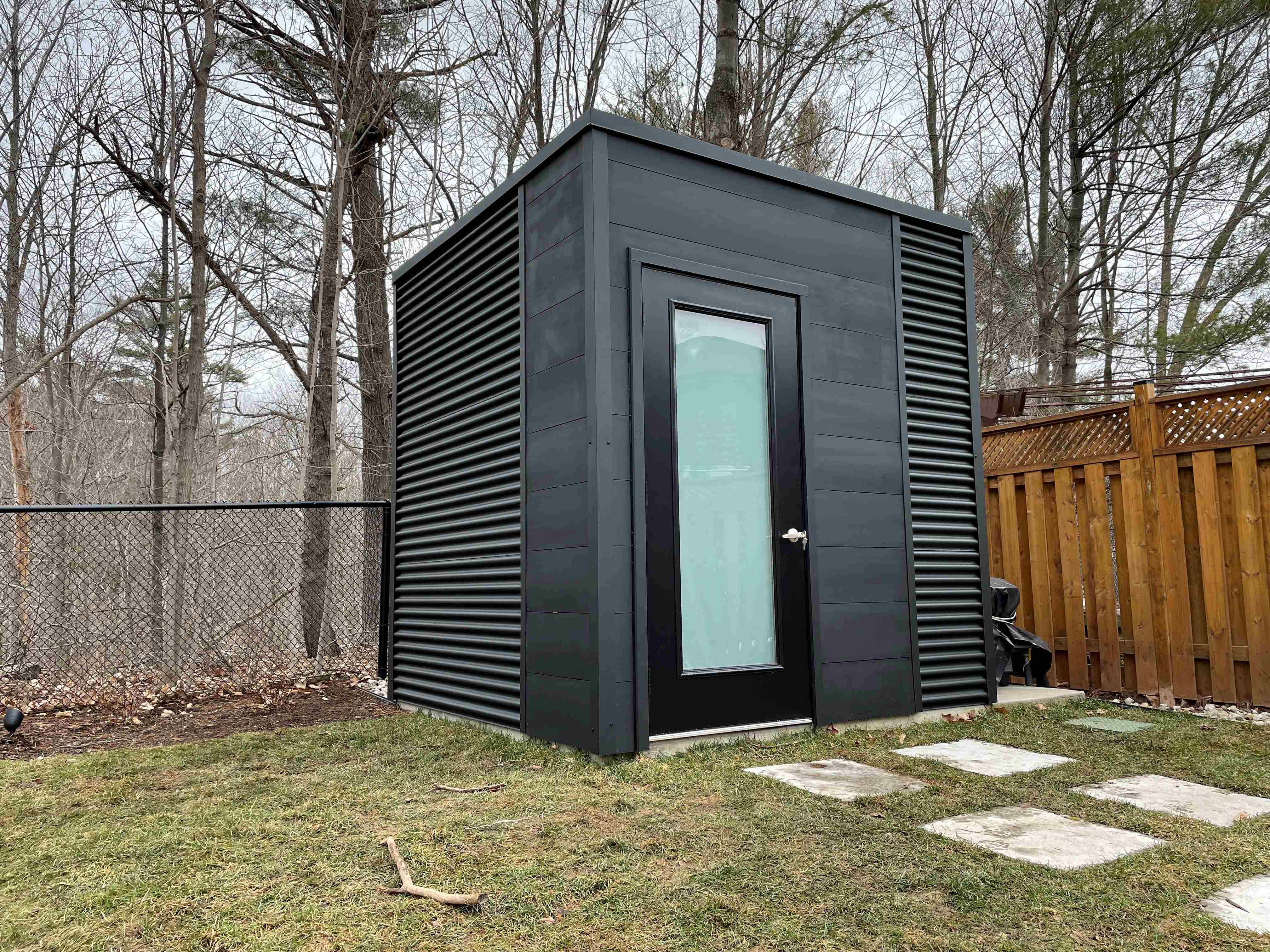 8x8 Cube Shed with Jet Black corrugated steel siding and stained pine tongue-and-groove front wall in Oakville Ontario, installed by Backyard Escape Studios.