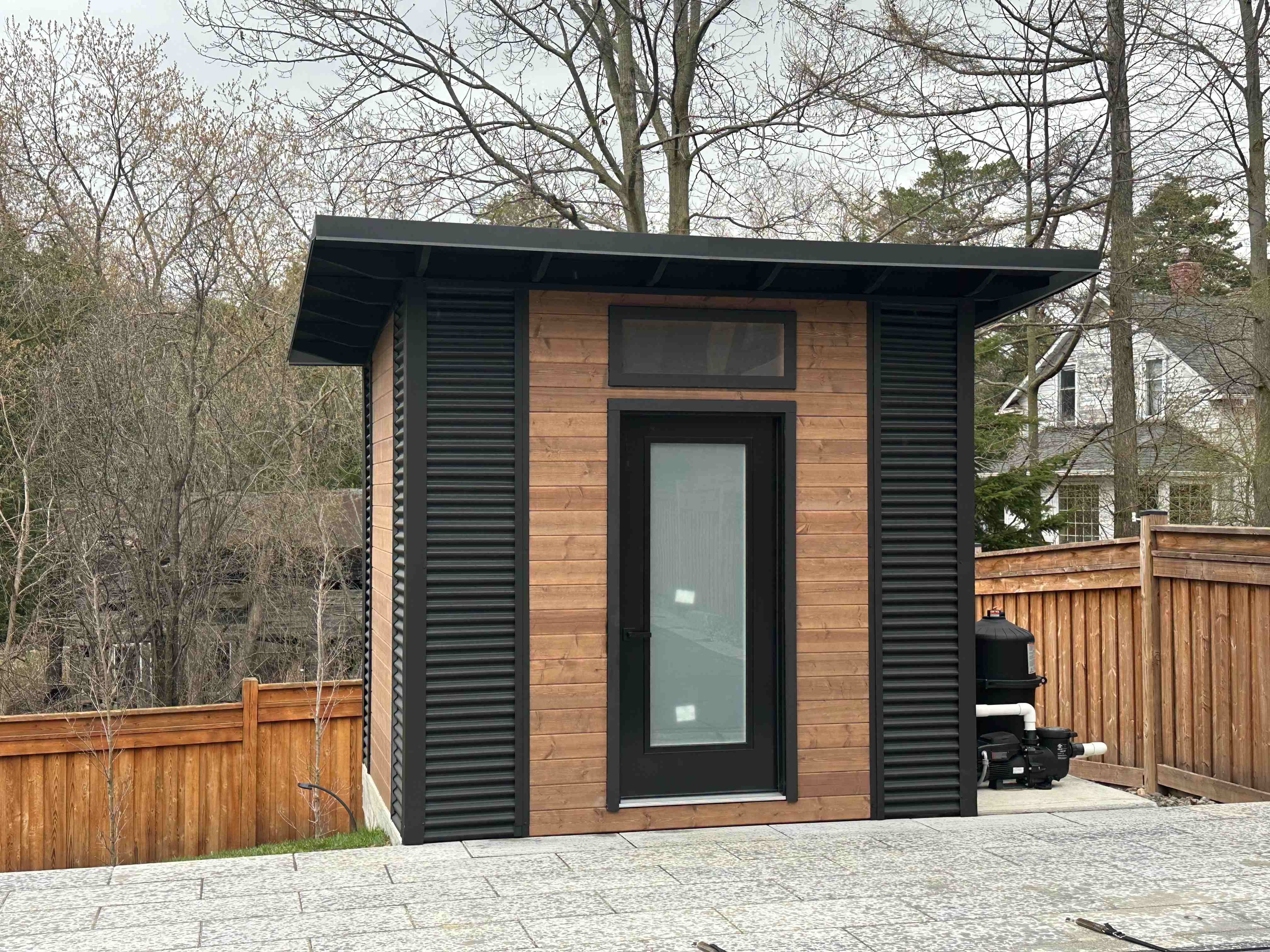 10x8 Advanced Shed with black corrugated steel siding and cedar-stained pine front wall installed in Aurora Ontario by Backyard Escape Studios.