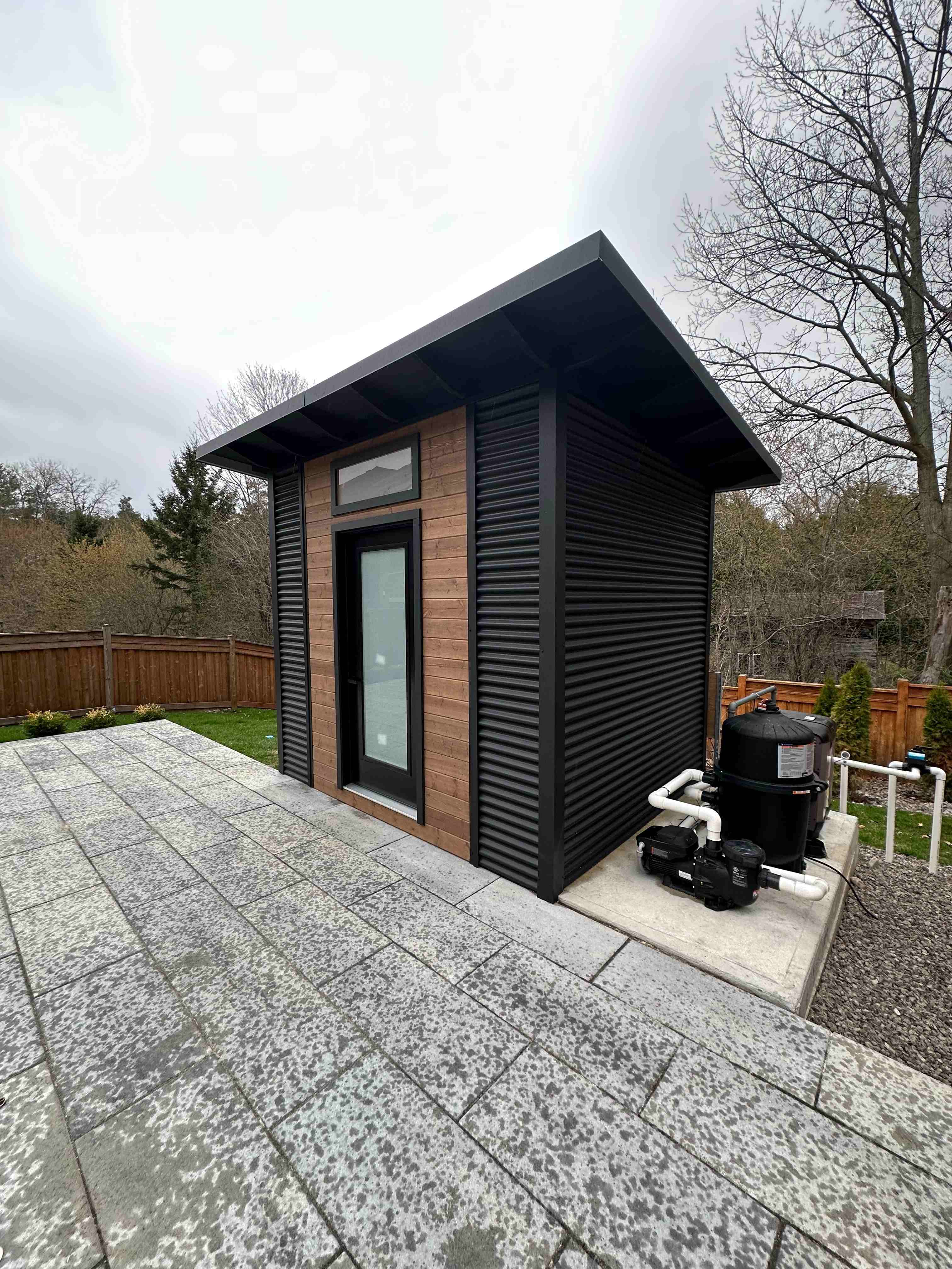 10x8 Advanced Shed with black corrugated steel siding and cedar-stained pine front wall with frosted glass door in Aurora Ontario