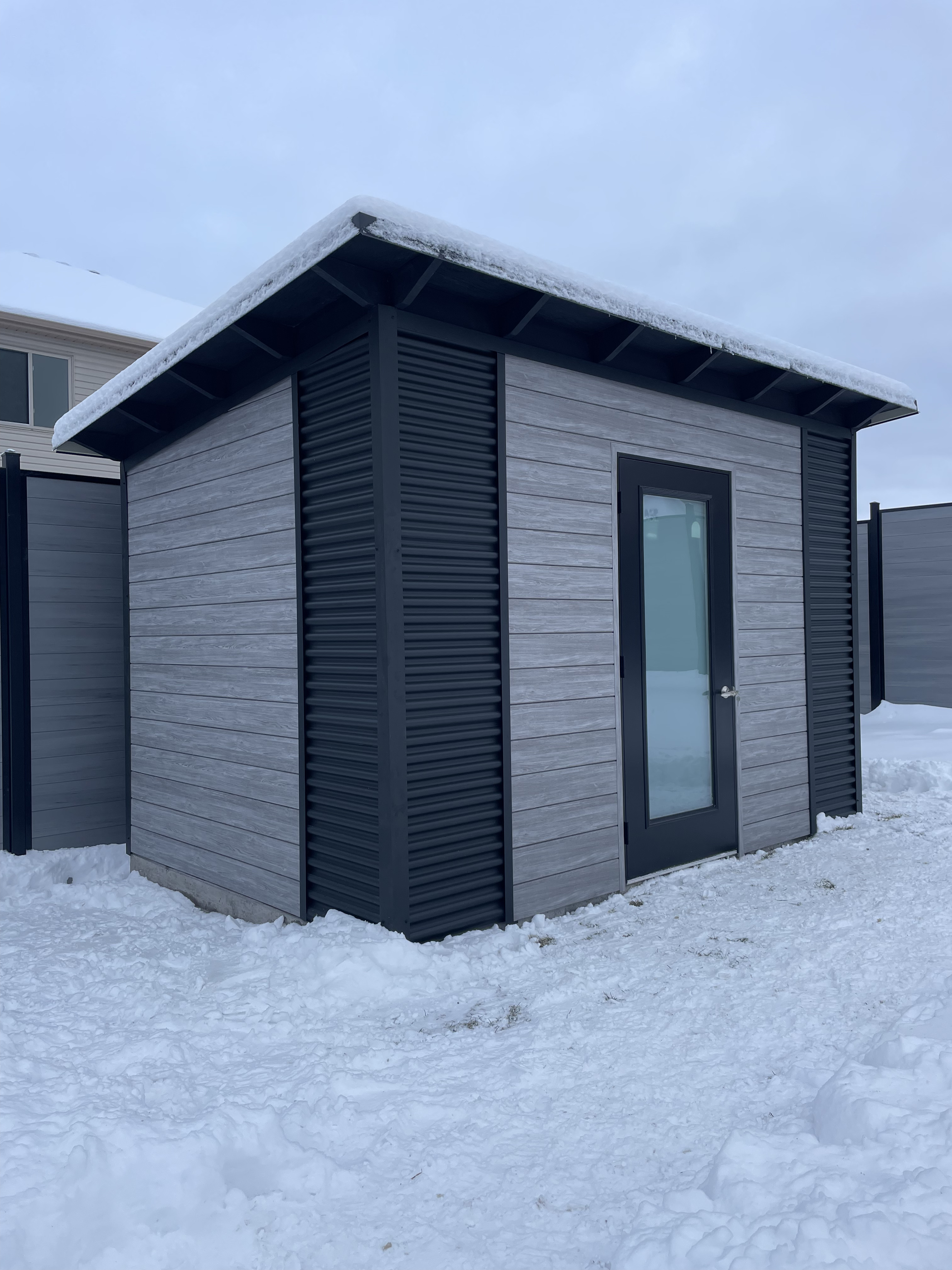 Front angle view of 12x8 Essential Shed with frosted glass outswing door and Barnboard Grey Chamclad shiplap exterior in Kitchener Ontario, installed by Backyard Escape Studios