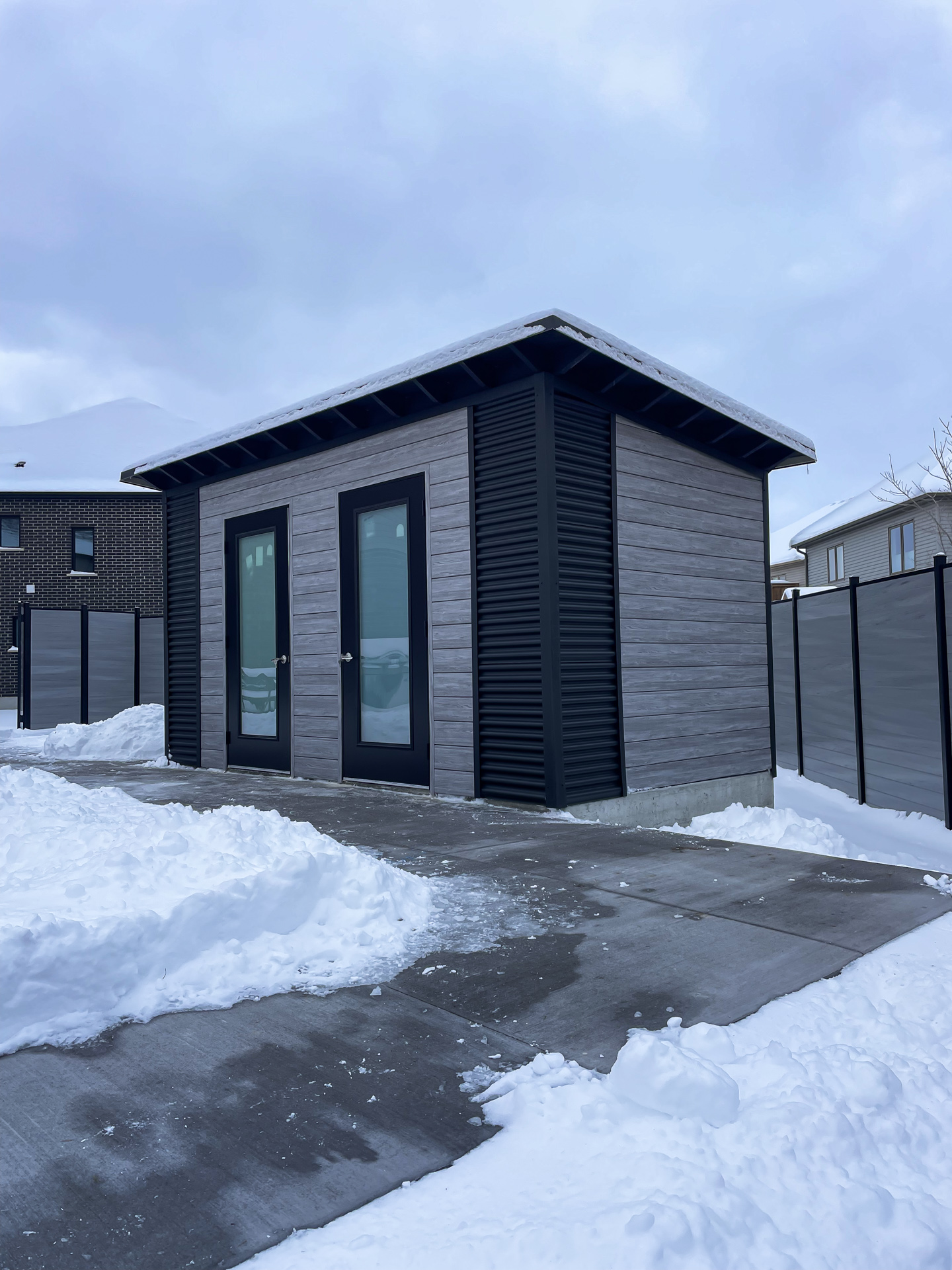 15x8 Essential Shed with Barnboard Grey Chamclad shiplap siding, Jet Black corrugated steel corner accents, and two frosted glass outswing doors in Kitchener Ontario, installed by Backyard Escape Studios.