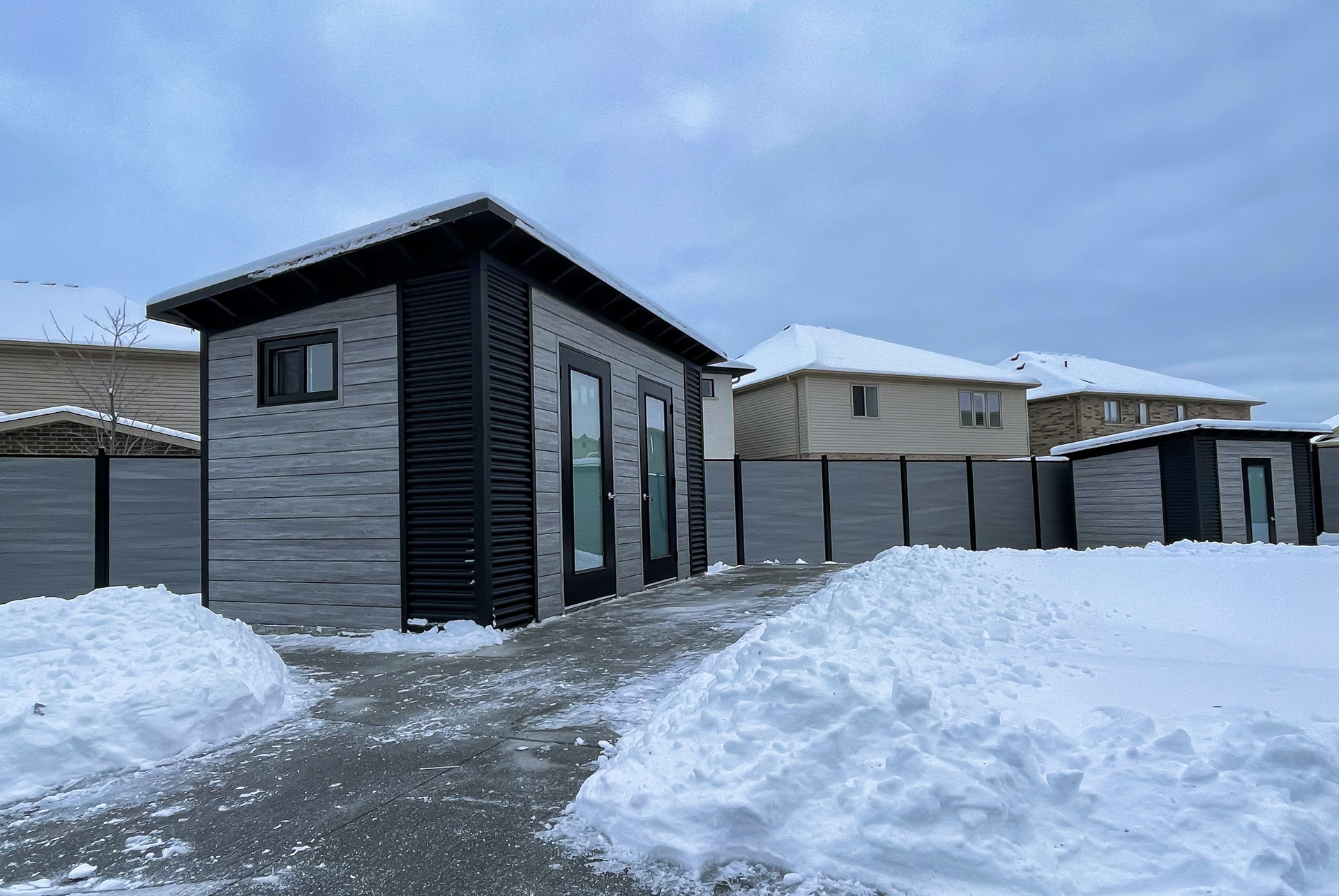 Side and rear angle of 15x8 Essential Shed showing slider window, Jet Black corrugated steel accents, and Barnboard Grey Chamclad shiplap in Kitchener Ontario, installed by Backyard Escape Studios.