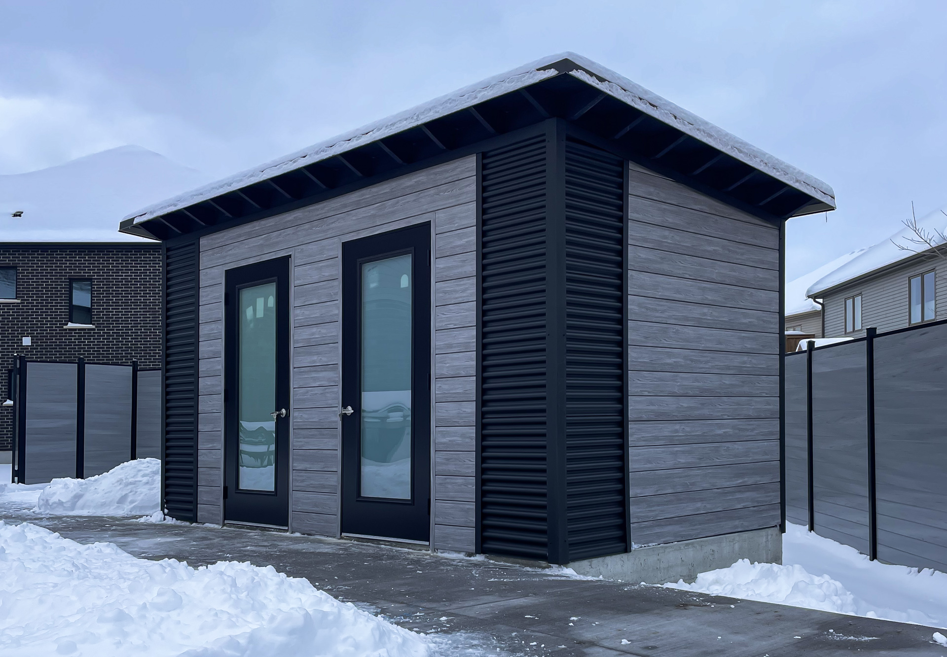 Front view of 15x8 Essential Shed with Barnboard Grey Chamclad shiplap, Jet Black steel accents, and two frosted glass outswing doors in Kitchener Ontario, installed by Backyard Escape Studios.